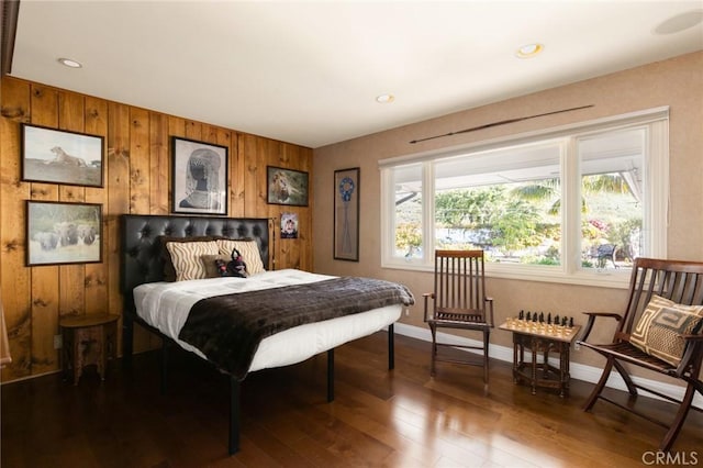 bedroom with wooden walls and dark wood-type flooring