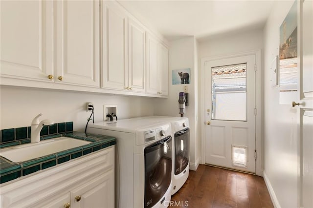 clothes washing area featuring dark hardwood / wood-style flooring, cabinets, sink, and washing machine and dryer