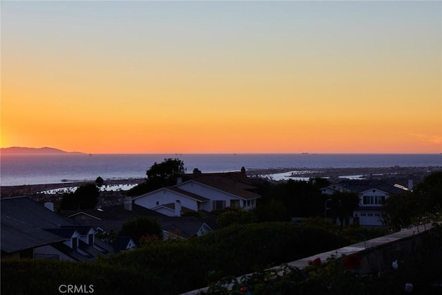 aerial view at dusk featuring a water view