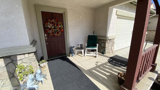 view of exterior entry with a porch and a garage