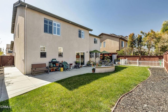 back of property featuring a patio area, a yard, a fenced backyard, and stucco siding