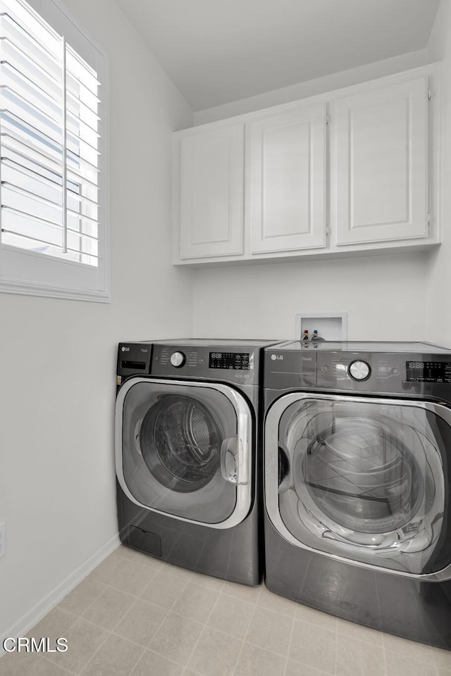 washroom with cabinet space, baseboards, and washer and clothes dryer