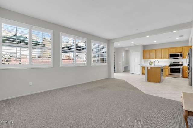 unfurnished living room with plenty of natural light, recessed lighting, light tile patterned flooring, and light colored carpet