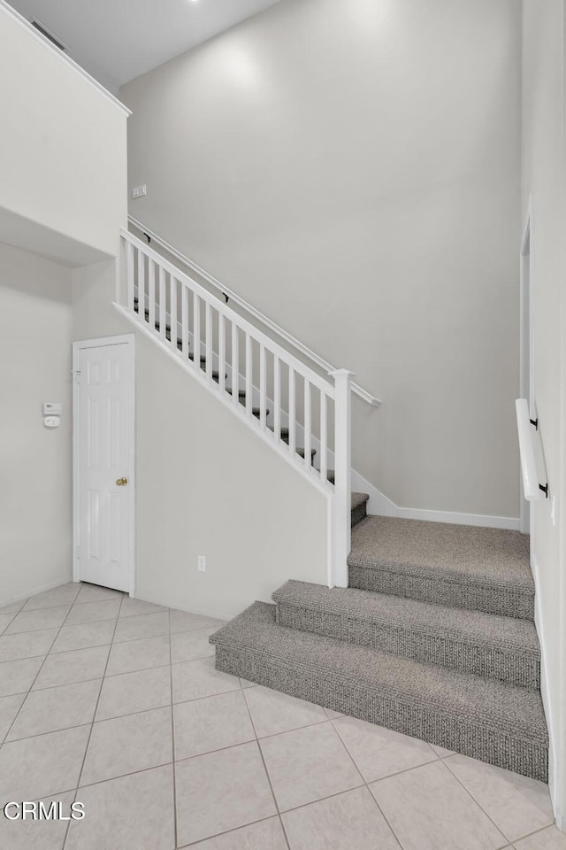 stairway with visible vents, a towering ceiling, and tile patterned floors