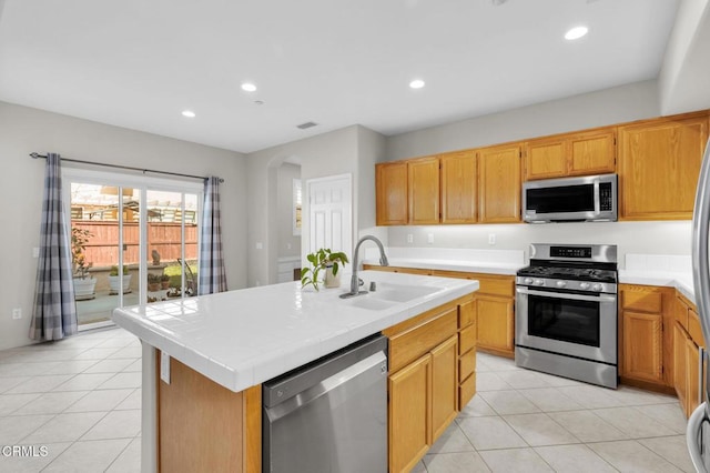 kitchen with appliances with stainless steel finishes, a sink, tile counters, and recessed lighting