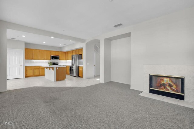 unfurnished living room featuring light tile patterned floors, recessed lighting, light colored carpet, a fireplace, and visible vents