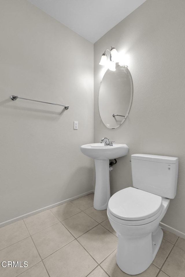 half bath with tile patterned flooring, toilet, and baseboards