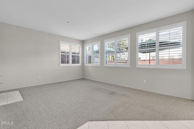 carpeted empty room featuring tile patterned floors and baseboards