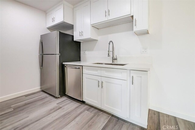 kitchen featuring white cabinetry, appliances with stainless steel finishes, sink, and light wood-type flooring