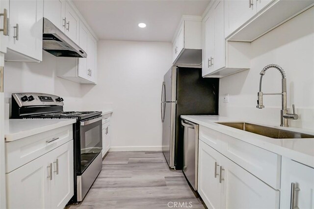 kitchen with stainless steel appliances, white cabinetry, sink, and light wood-type flooring