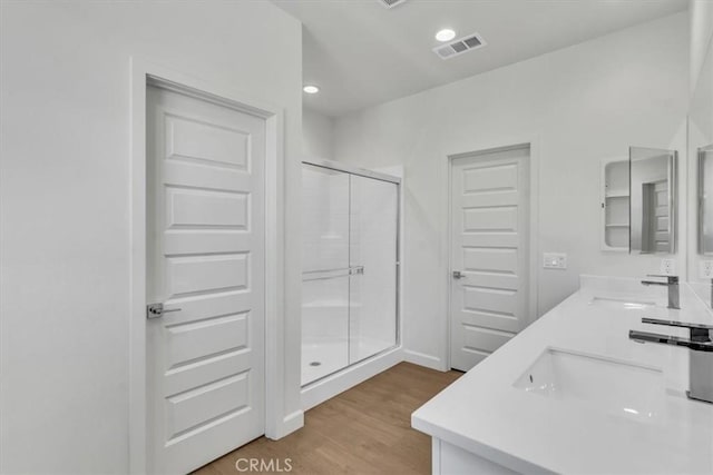 bathroom with vanity, a shower with shower door, and hardwood / wood-style floors