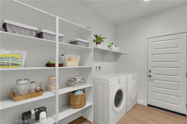 laundry room with washing machine and dryer and light hardwood / wood-style floors