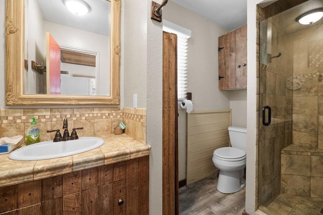 bathroom featuring walk in shower, sink, tile walls, hardwood / wood-style floors, and toilet