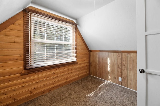 additional living space featuring carpet, wood walls, and lofted ceiling