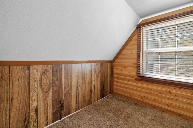 bonus room with carpet flooring, wood walls, and vaulted ceiling