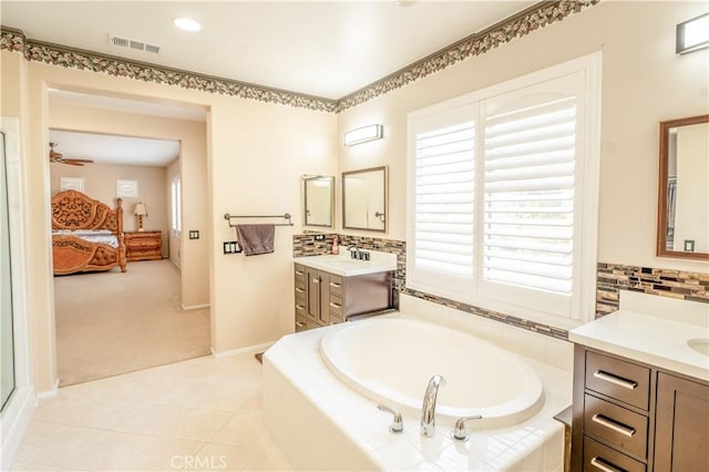 bathroom with tile patterned floors, vanity, ceiling fan, and tiled bath