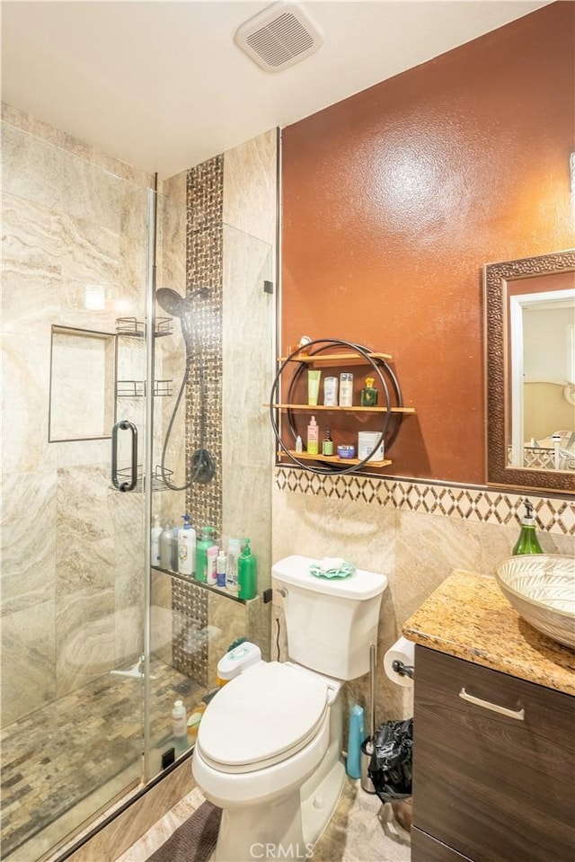 bathroom featuring vanity, toilet, walk in shower, and tile walls