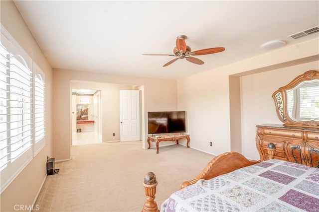 bedroom with ceiling fan, ensuite bathroom, and light carpet