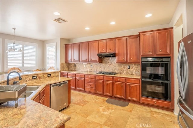 kitchen with backsplash, sink, appliances with stainless steel finishes, decorative light fixtures, and light stone counters