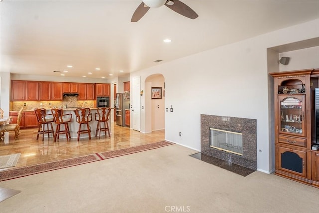 living room featuring ceiling fan, a fireplace, and light carpet