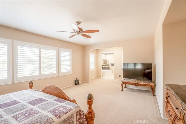 bedroom with ceiling fan, light colored carpet, and connected bathroom