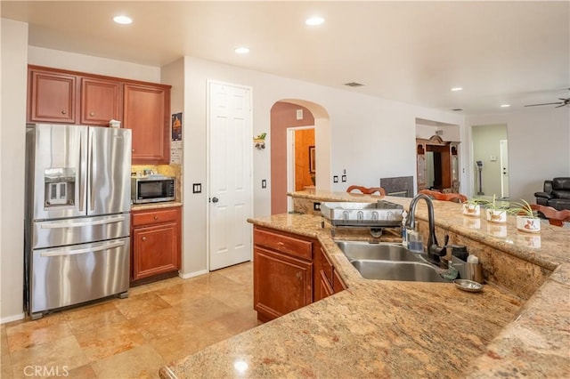 kitchen featuring light stone countertops, sink, ceiling fan, and appliances with stainless steel finishes