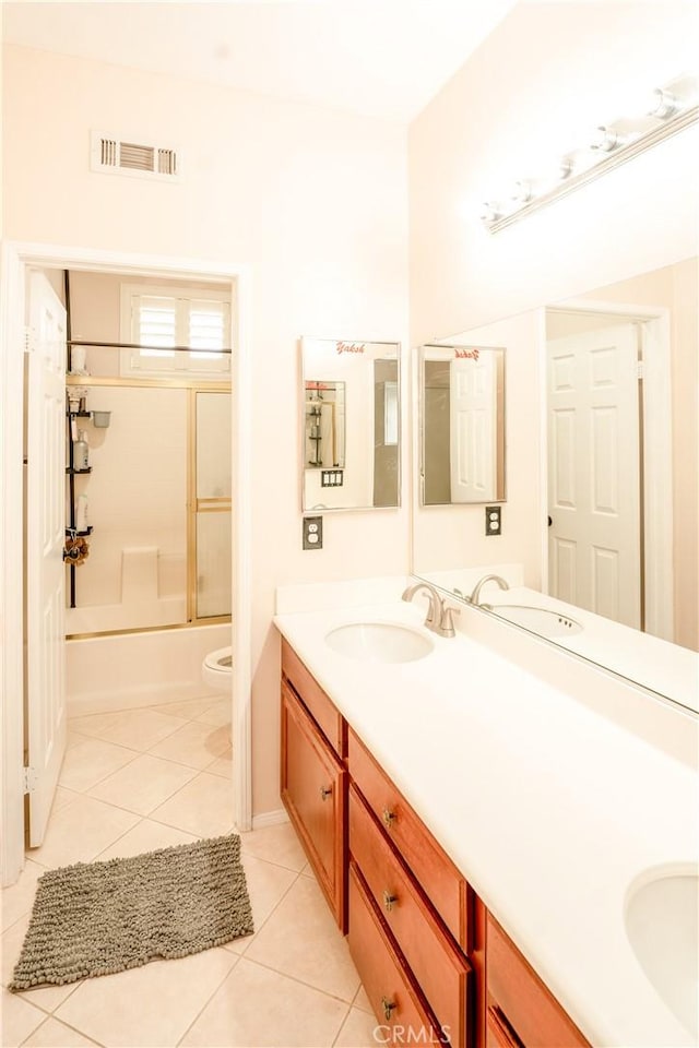 full bathroom with combined bath / shower with glass door, vanity, tile patterned floors, and toilet