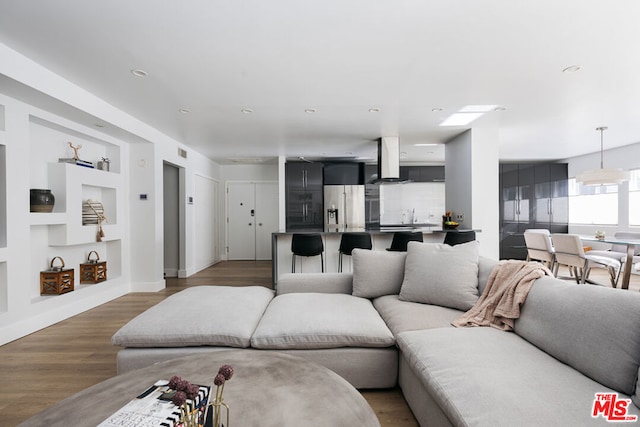 living room featuring dark wood-type flooring, built in shelves, and sink