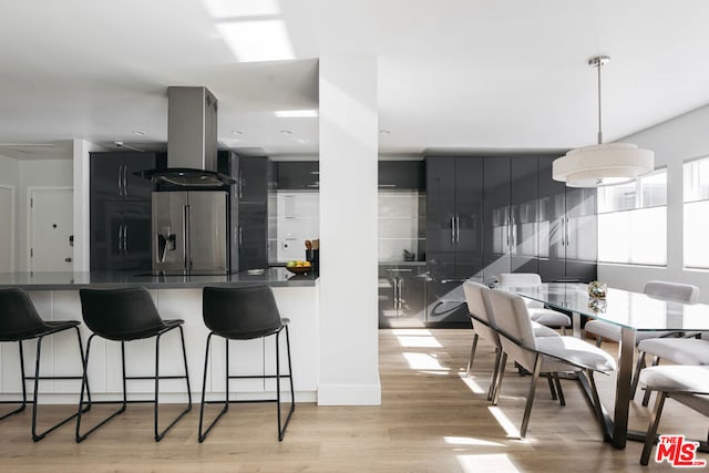 kitchen with island exhaust hood, stainless steel fridge, kitchen peninsula, and light hardwood / wood-style flooring