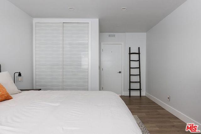 bedroom with dark wood-type flooring and a closet