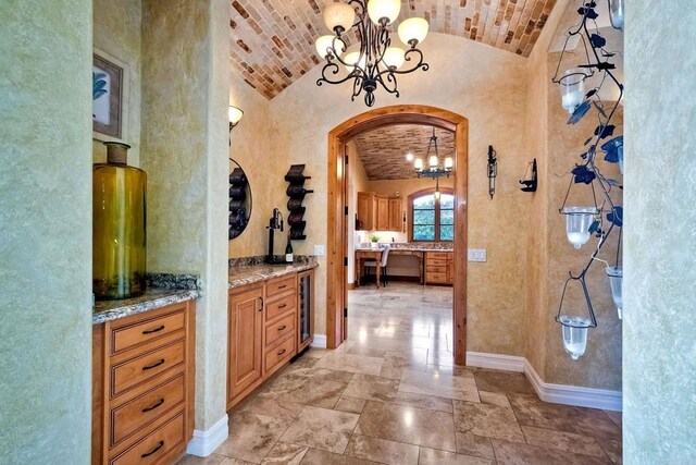 hallway featuring wine cooler, an inviting chandelier, and vaulted ceiling