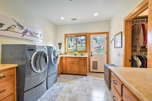 laundry room with washing machine and clothes dryer and cabinets