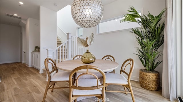 dining space with light wood-type flooring and a notable chandelier