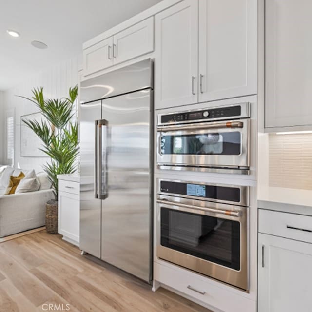 kitchen with white cabinets, stainless steel appliances, and light wood-type flooring