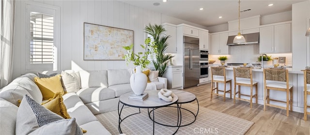 living room with light hardwood / wood-style flooring and wooden walls