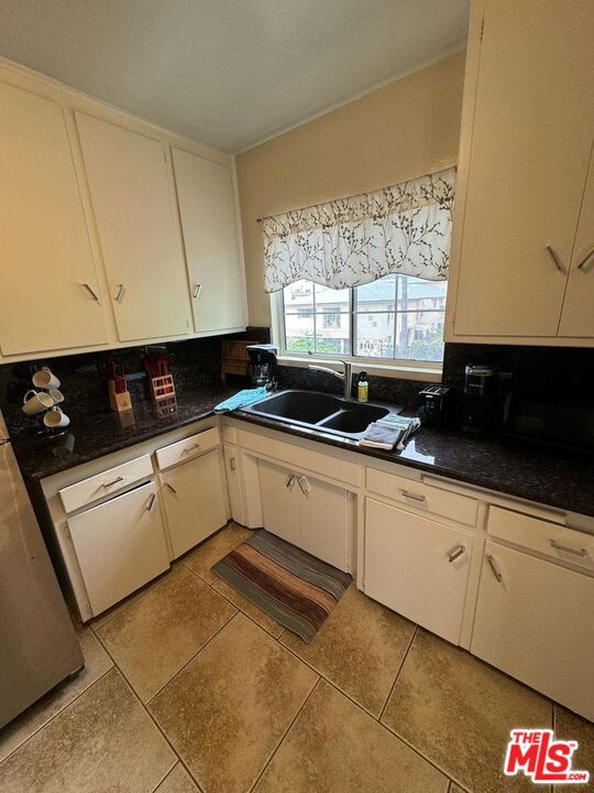 kitchen featuring backsplash, sink, white cabinets, and light tile patterned flooring