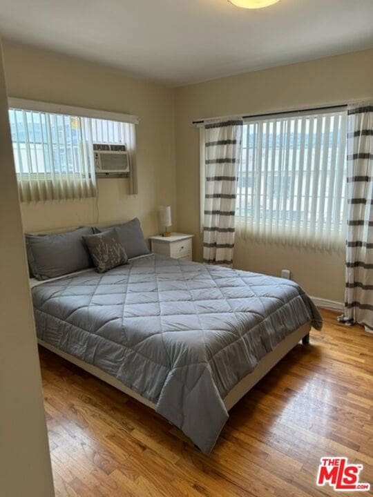 bedroom featuring hardwood / wood-style floors, cooling unit, and multiple windows