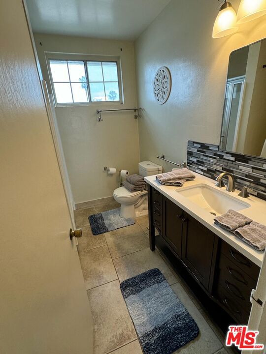 bathroom with decorative backsplash, tile patterned flooring, vanity, and toilet