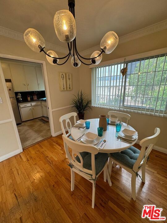 dining space with a notable chandelier, ornamental molding, and light hardwood / wood-style flooring