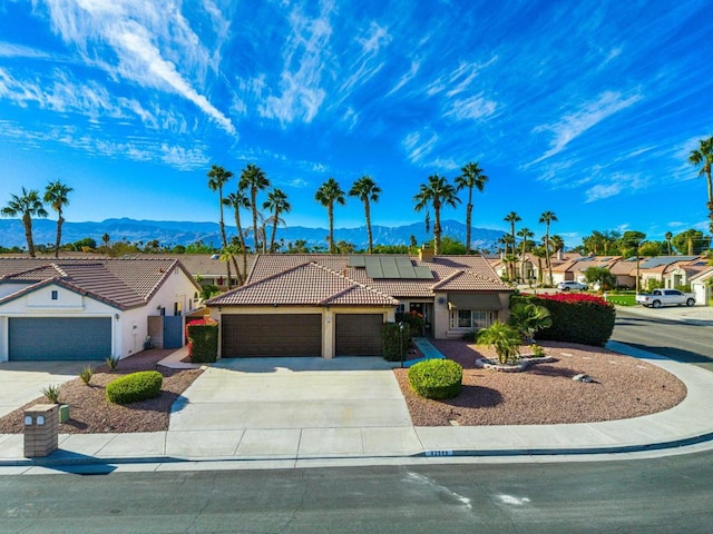 view of front of home featuring a mountain view, a garage, and solar panels