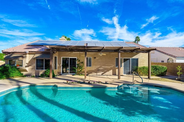 back of property featuring a fenced in pool, a patio area, ceiling fan, and solar panels