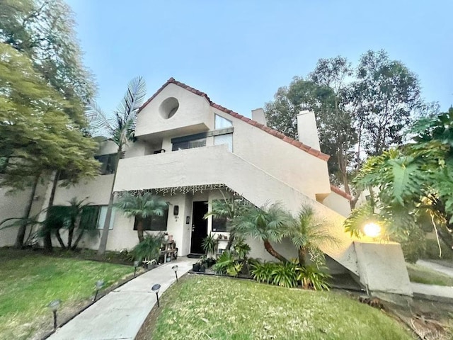 mediterranean / spanish home featuring a balcony and a front lawn