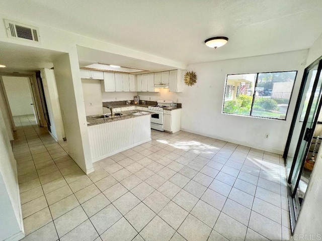 kitchen featuring white cabinetry, white range with gas cooktop, sink, and light tile patterned floors