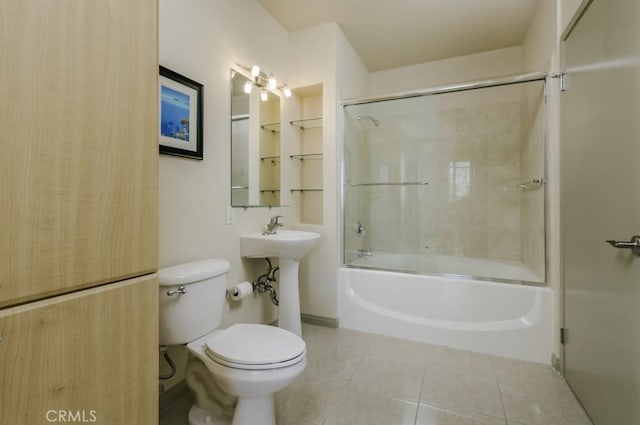 full bathroom featuring sink, shower / bath combination with glass door, toilet, and tile patterned flooring