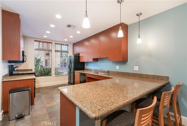 kitchen with pendant lighting, black appliances, a kitchen bar, sink, and kitchen peninsula