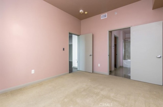 unfurnished bedroom with light colored carpet and ensuite bathroom