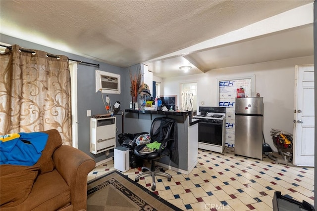 kitchen with a wall mounted air conditioner, white cabinets, stainless steel fridge, a textured ceiling, and gas range gas stove