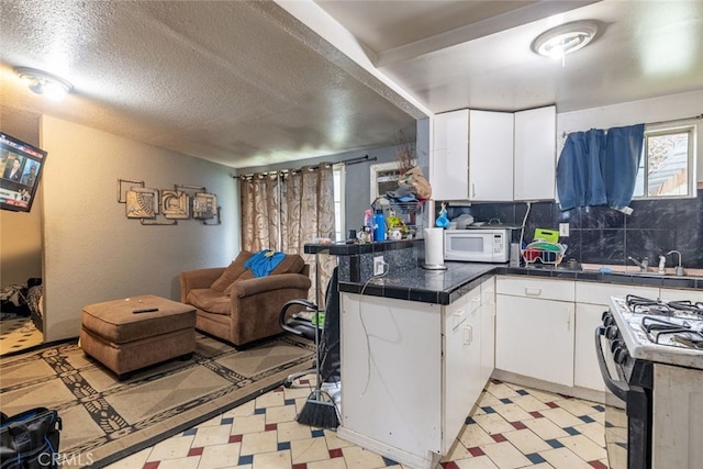 kitchen with white cabinets, kitchen peninsula, a textured ceiling, and tasteful backsplash