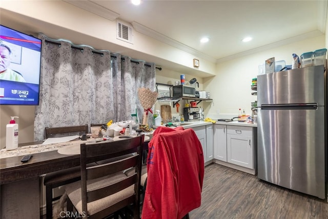 kitchen featuring dark hardwood / wood-style flooring, white cabinetry, crown molding, and appliances with stainless steel finishes