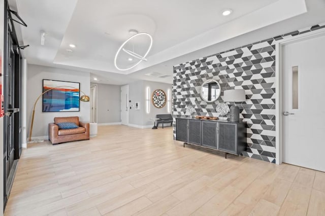 living room with tile walls, light hardwood / wood-style flooring, and a raised ceiling